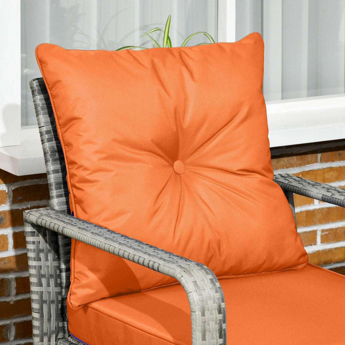 Grey wicker armchair with orange cushion and tufted back detail