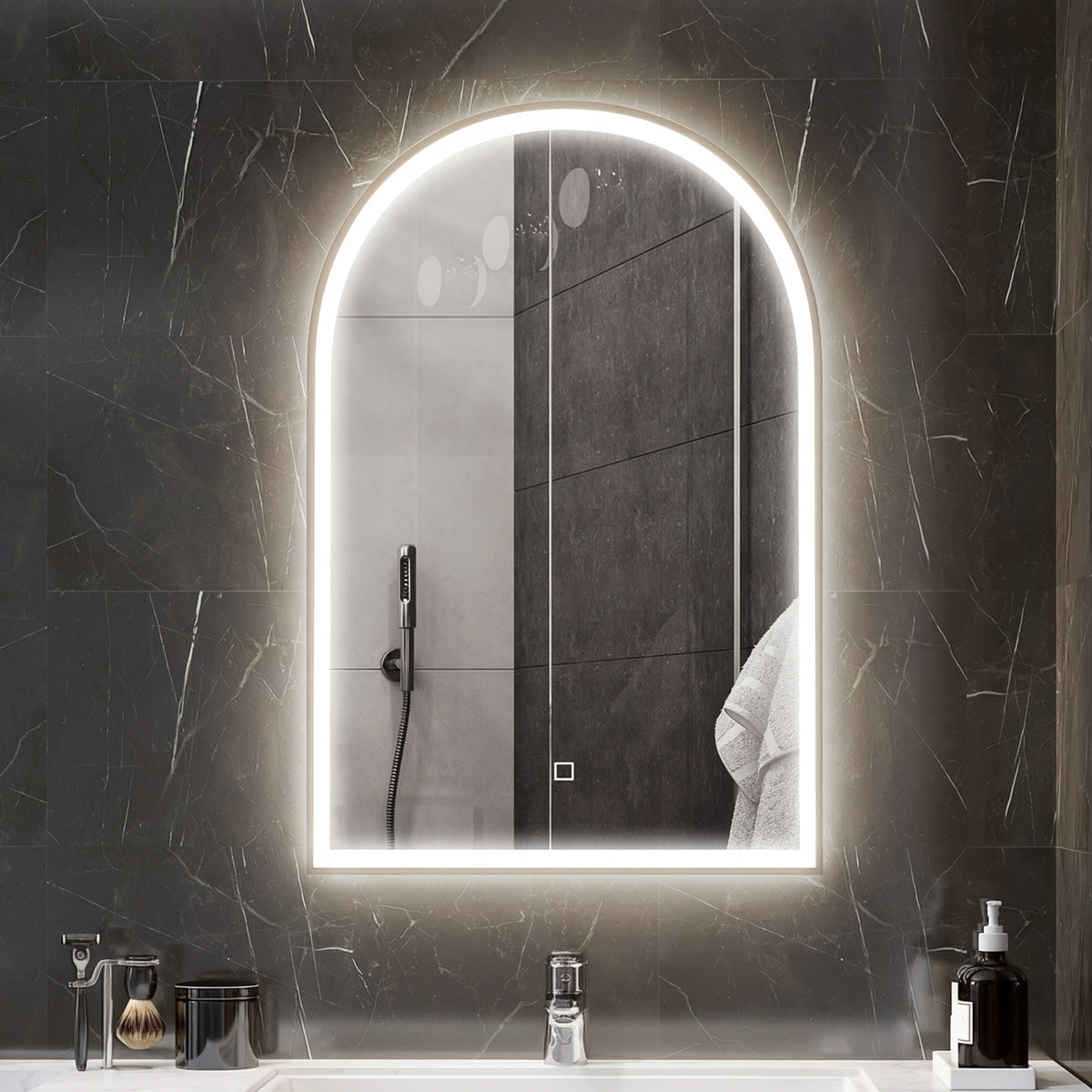 Arched gold LED bathroom mirror with bright lit border on dark tiled wall