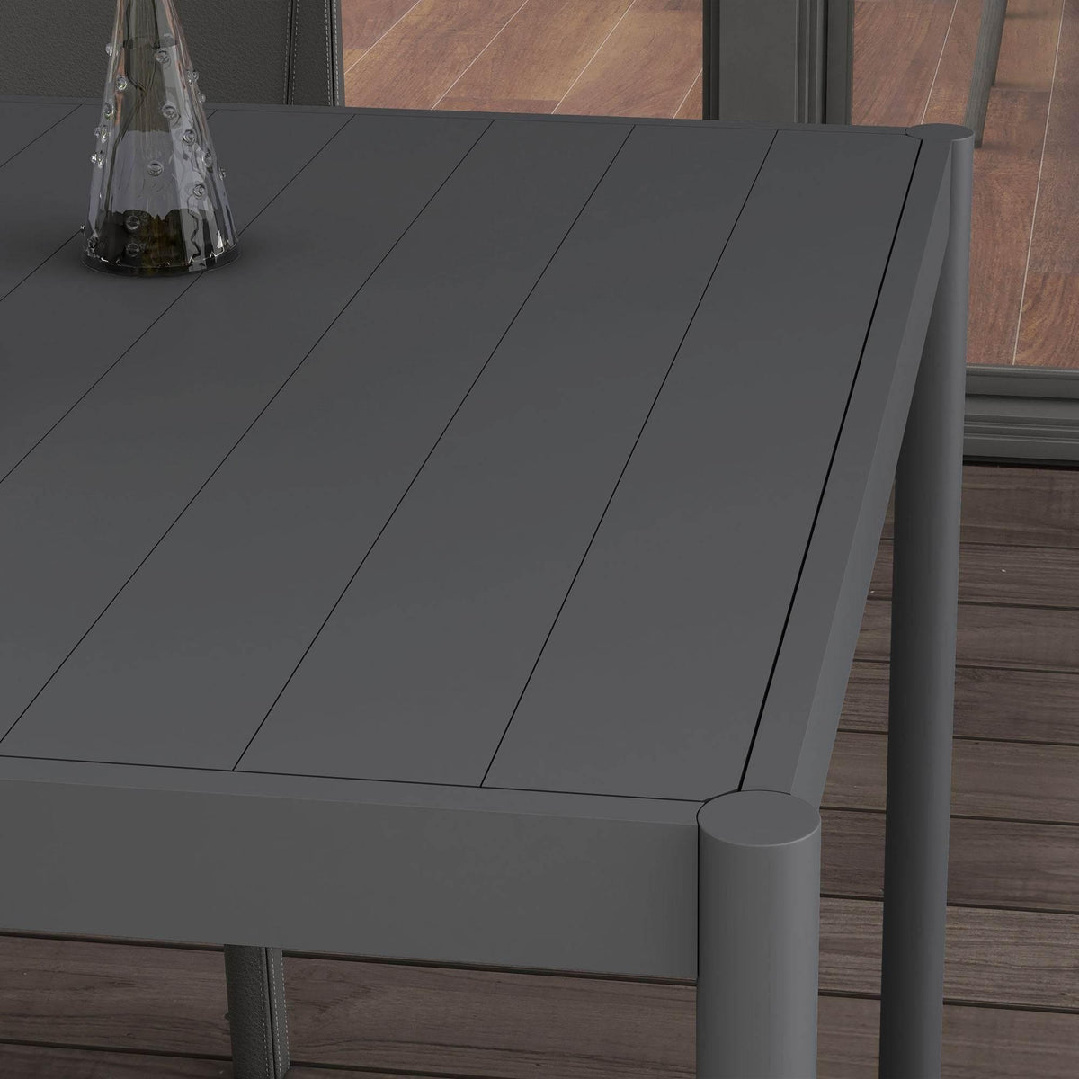 Close-up of dark gray slat-style outdoor dining table top and rounded corner leg