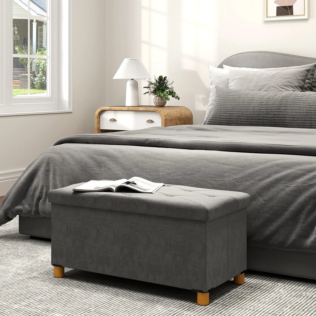 Grey velvet upholstered storage ottoman with hinged top and wooden block legs