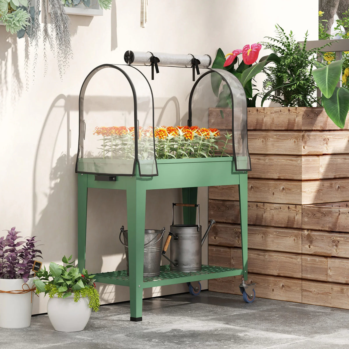 Green raised planter with arched greenhouse cover and metal watering accessories