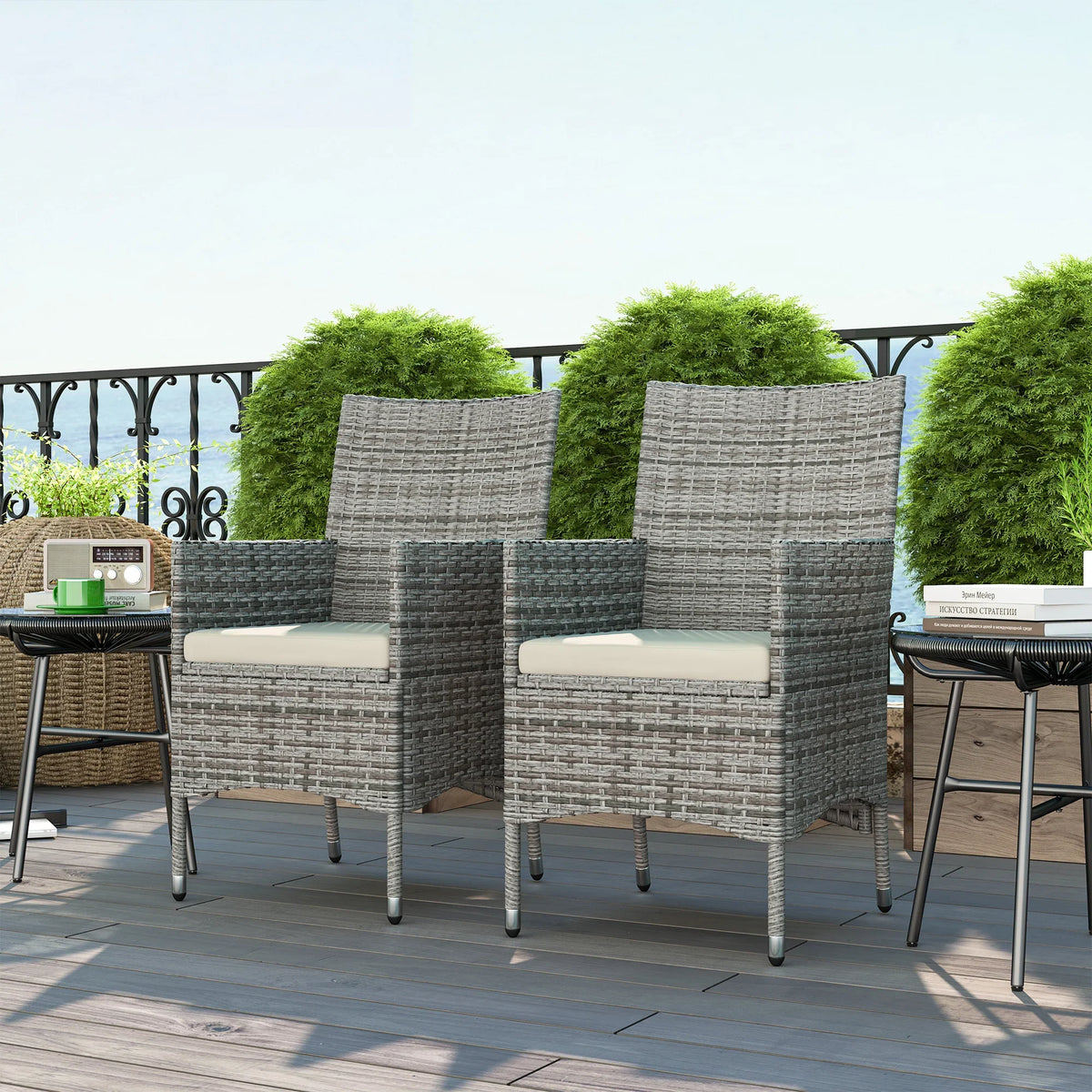 Set of two grey rattan chairs with cream seat cushions on outdoor patio