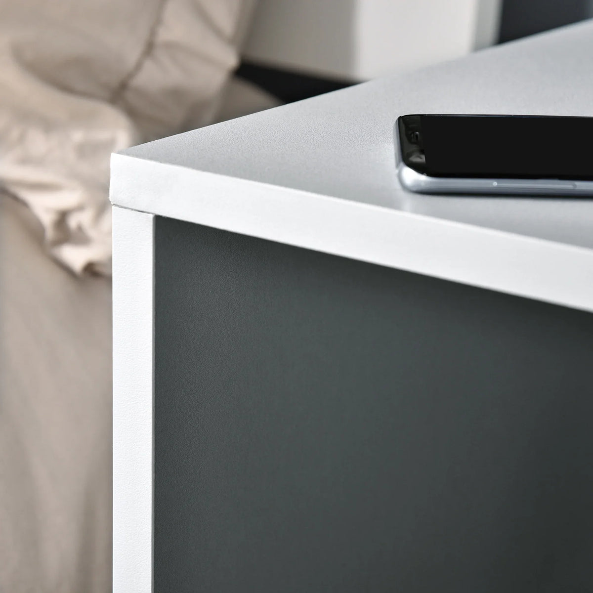 White-edged grey side table corner with black hardware detail under the top