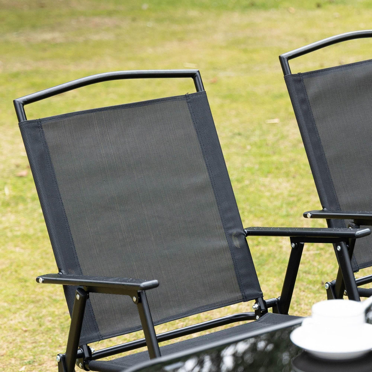 Single folding patio chair with dark mesh back and seat on black metal frame