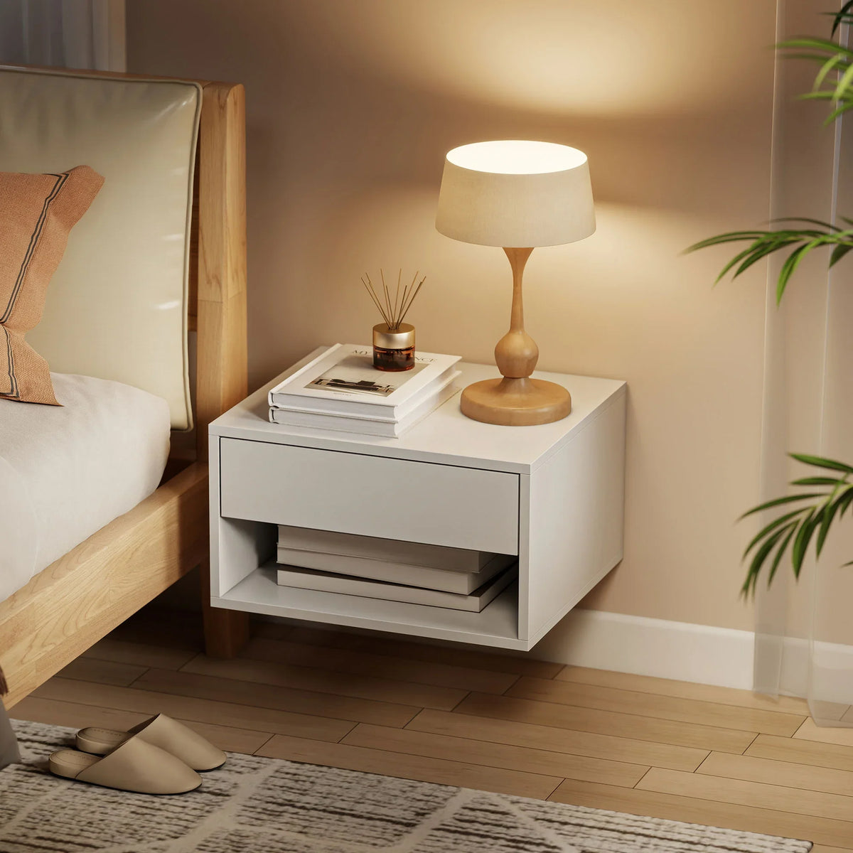 White floating bedside table with drawer and open shelf holding a lamp on top