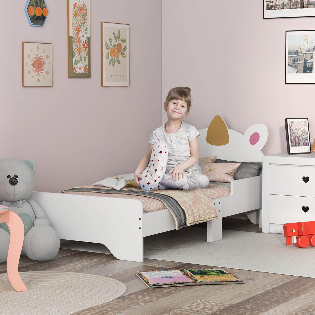 White unicorn toddler bed with horn-and-ear headboard, toddler sitting on mattress