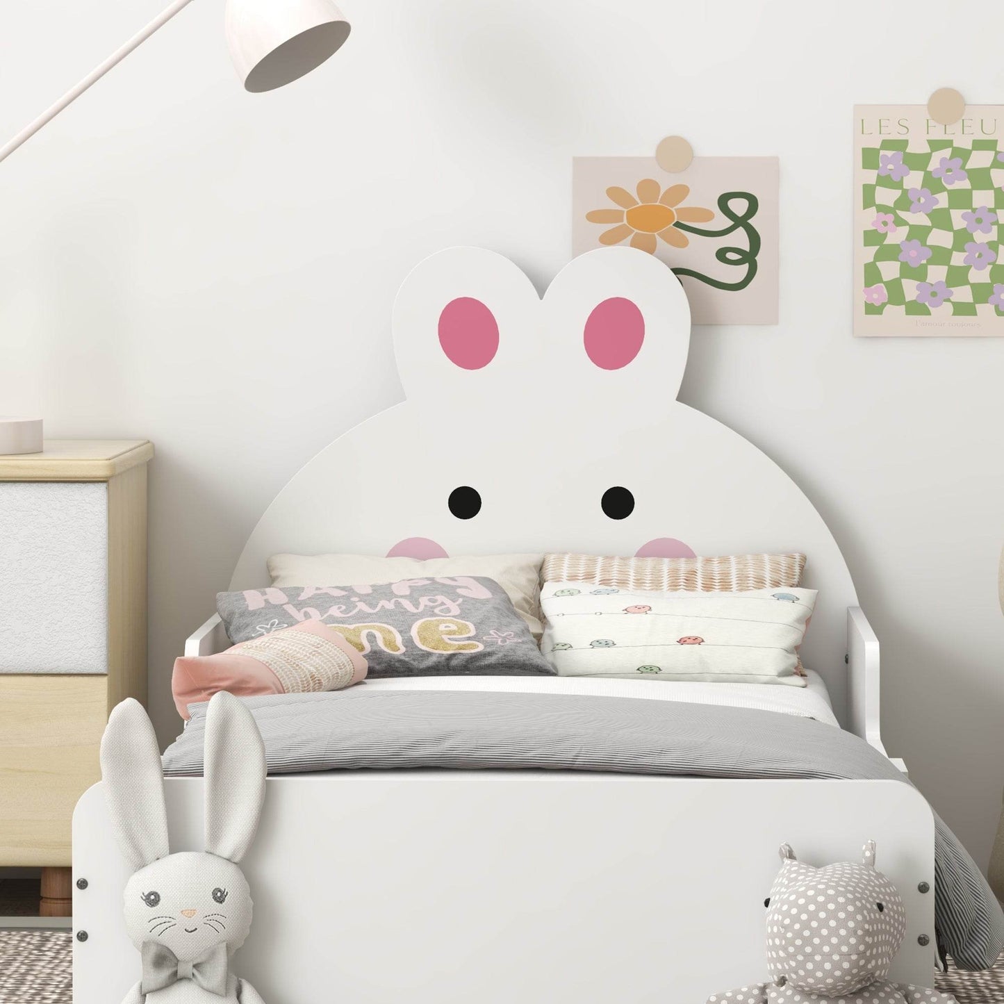 White toddler bed frame with bunny headboard, side rails, and pillows on the bed