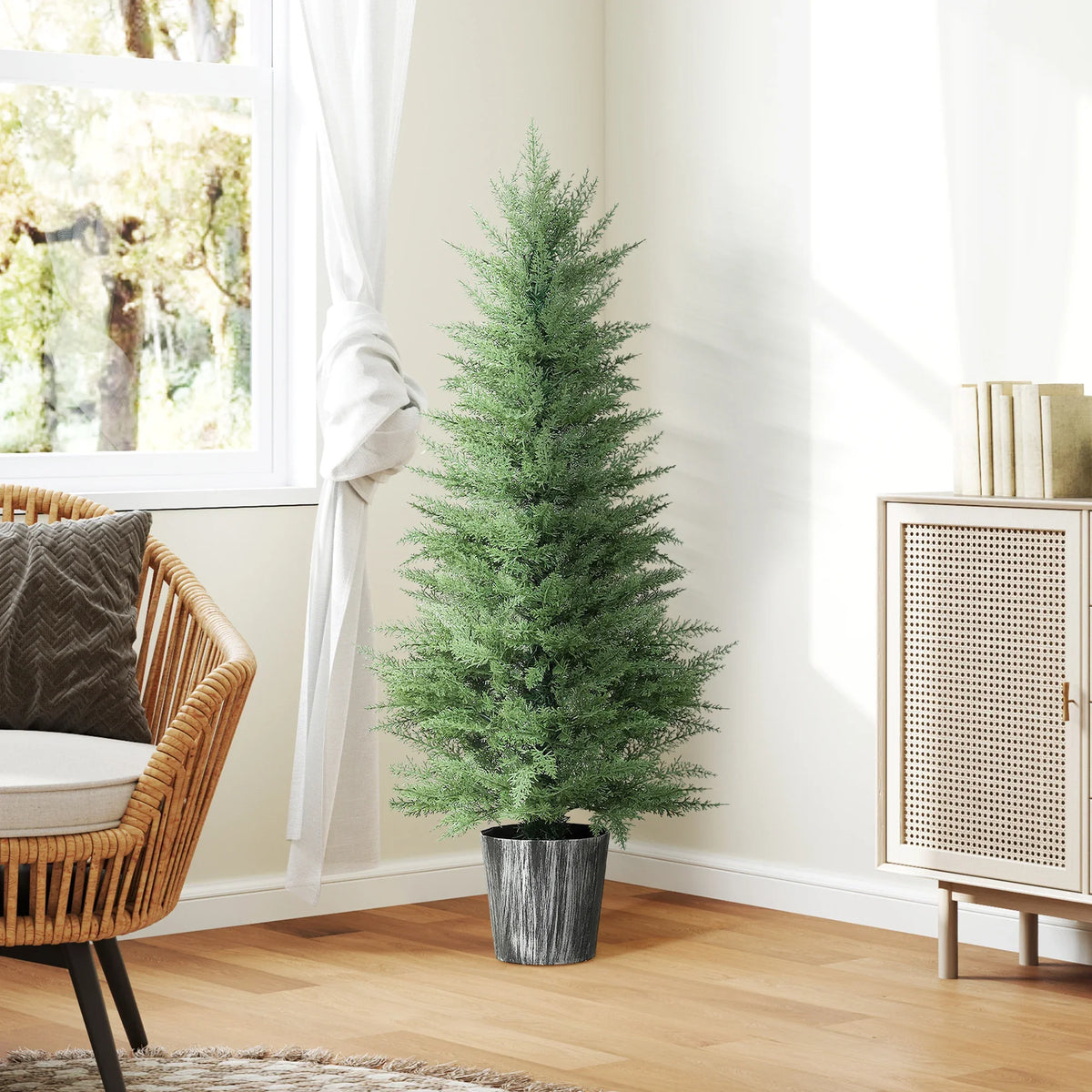 Tall artificial cypress tree in black pot beside sofa and rattan chair