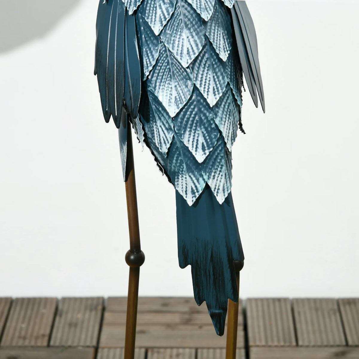 Close-up of a standing crane ornament with blue feathered body and metal legs