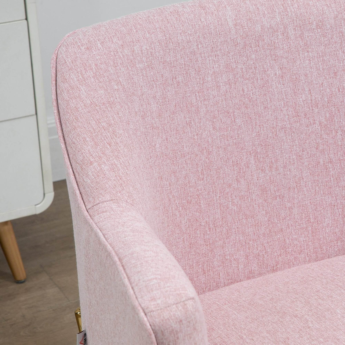Pink upholstered armchair with curved back and thick armrests, close-up