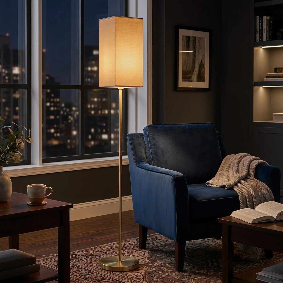 Gold standing floor lamp with rectangular faux linen shade glowing near armchair