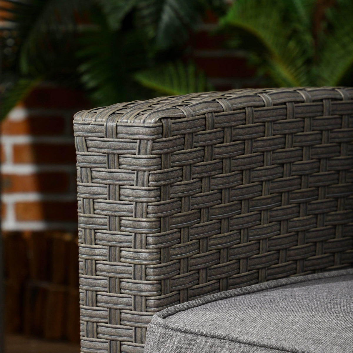 Grey woven rattan corner detail with fabric cushion edge and armrest contour