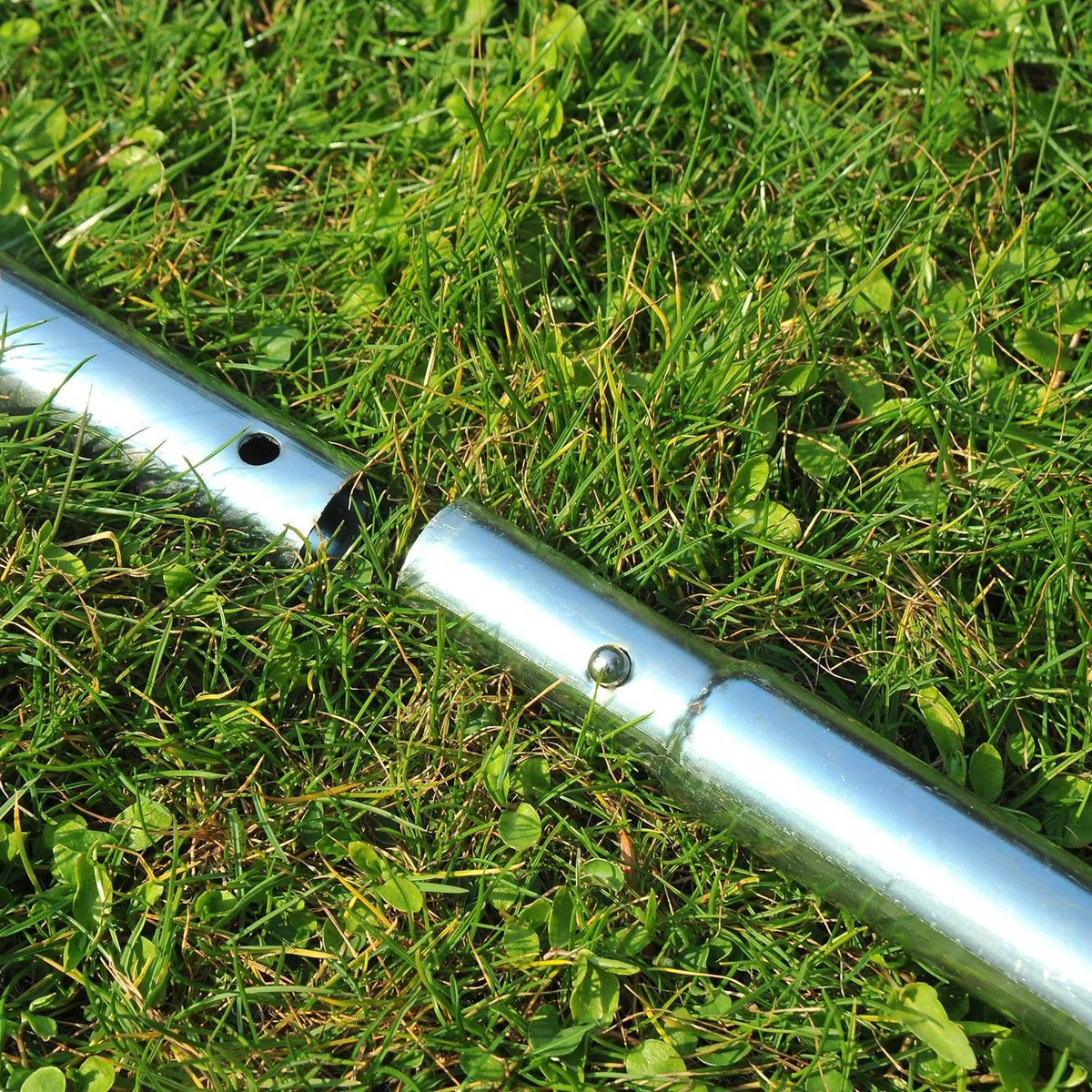 Metal spike tool for lawn aeration lying on grass