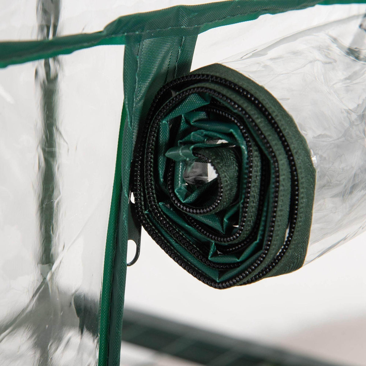 Rolled green roll-up door fabric with zipper edge on clear greenhouse cover