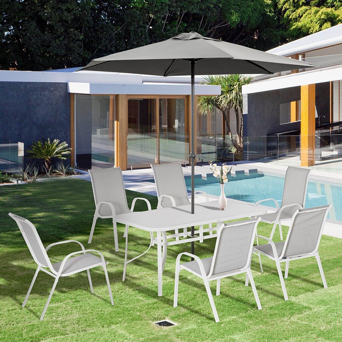 White patio dining set with table and armchairs on outdoor lawn
