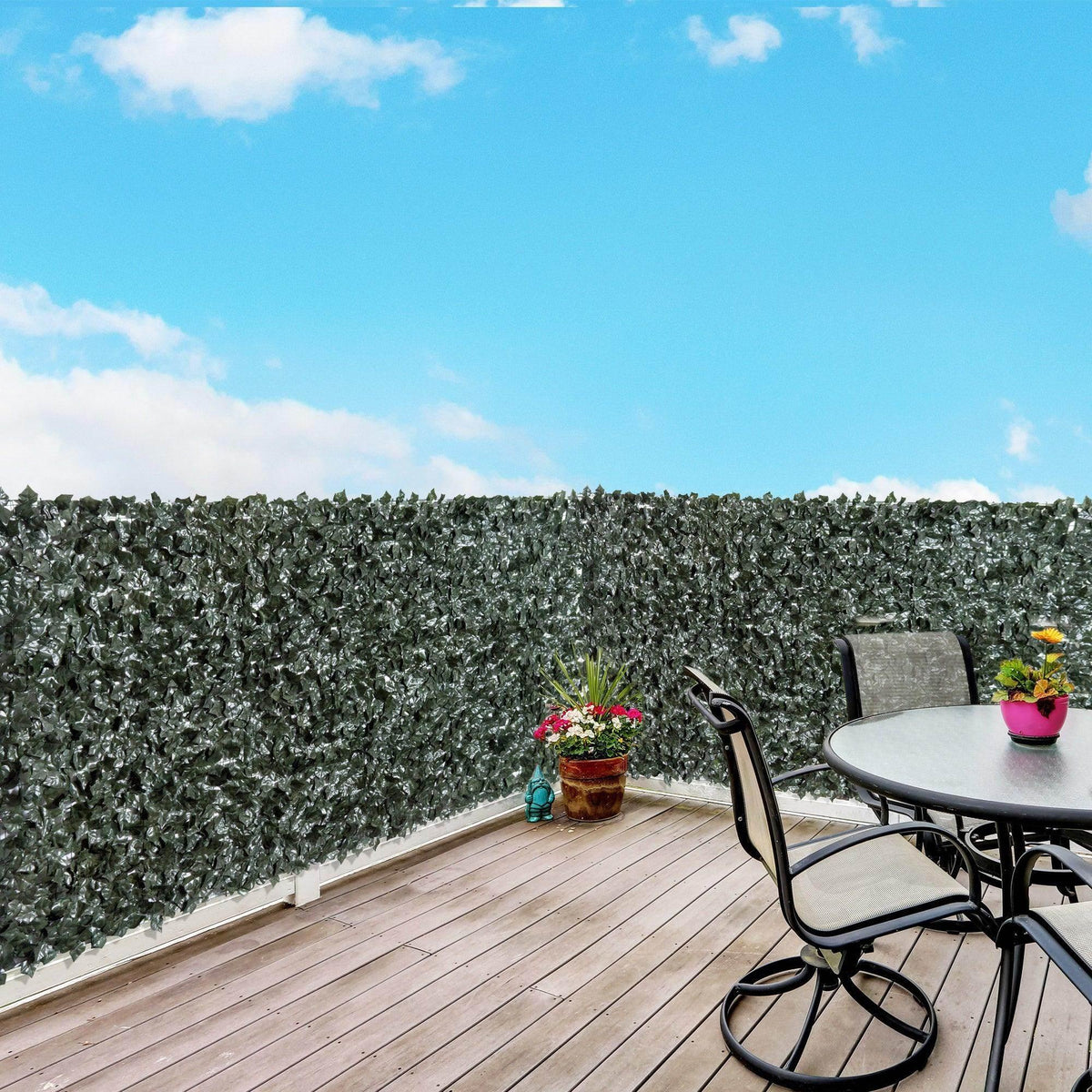 Dark green artificial leaf privacy screen panel with dense foliage along a patio