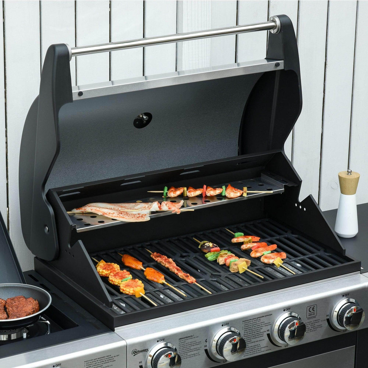 BBQ grill with lid open and skewers and vegetables on dark grates