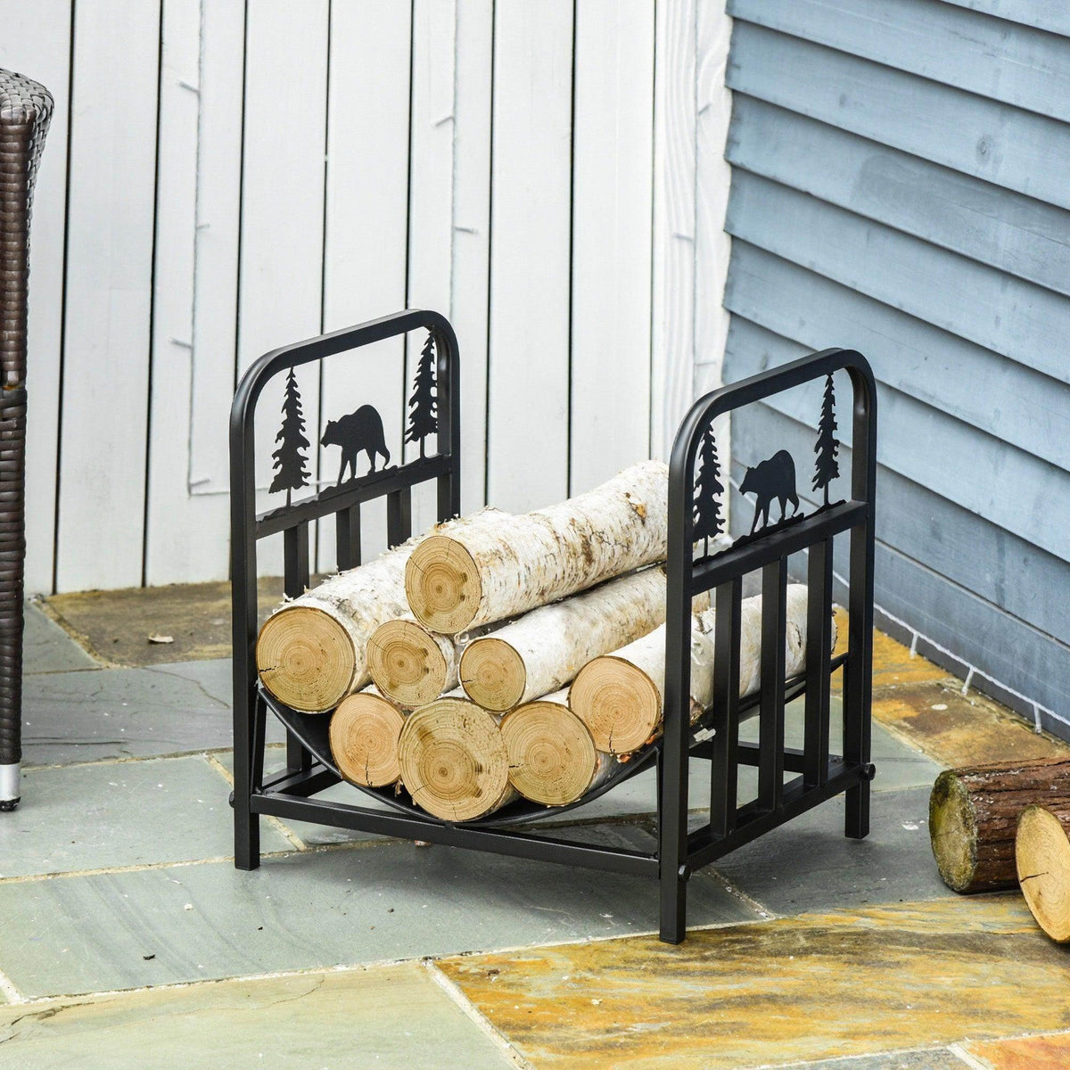 Black log rack with bear-and-tree cutouts holding firewood logs against a wall.