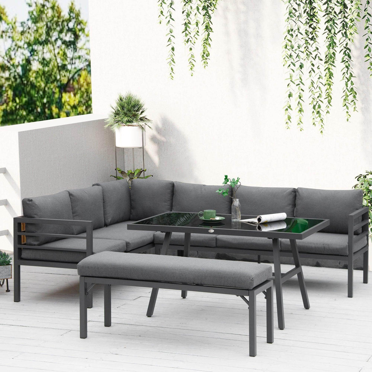 Gray L-shaped outdoor dining set with cushioned corner bench and glass-top table