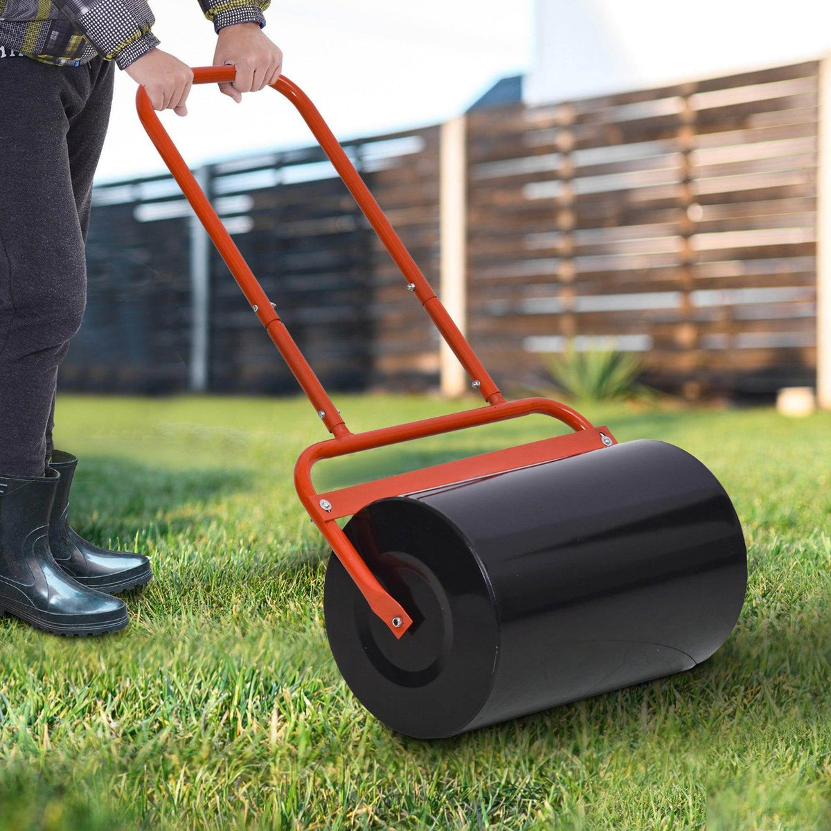 Lawn roller with orange handle and black filled cylinder, pushed on grass