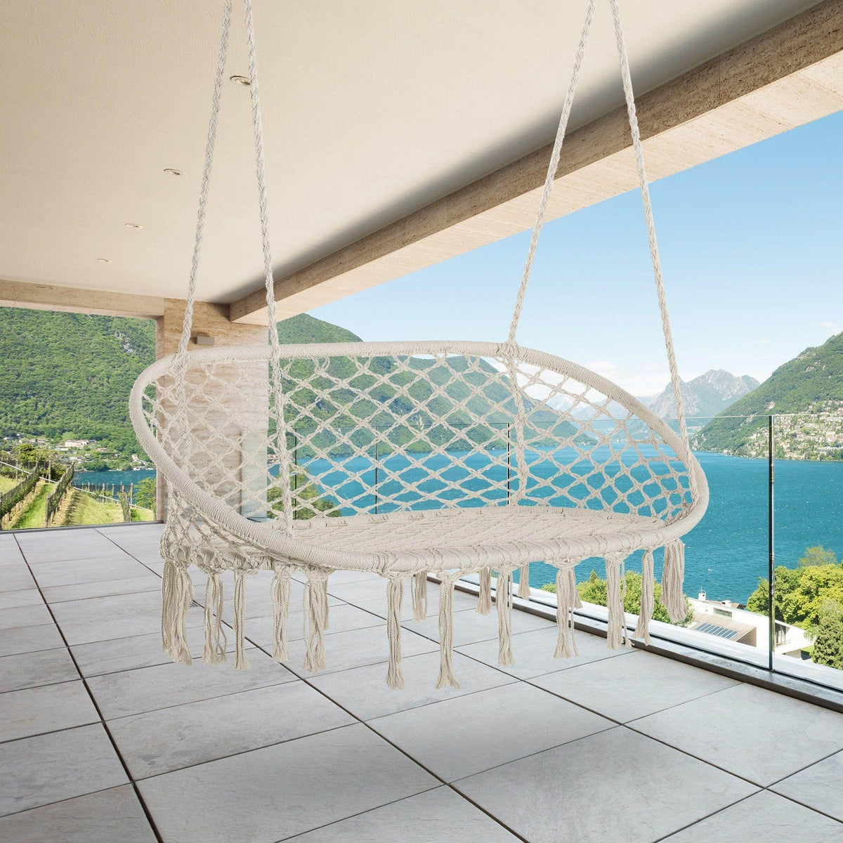 Outdoor macrame hammock chair with turquoise cushion, round net seat, and fringe tassels.