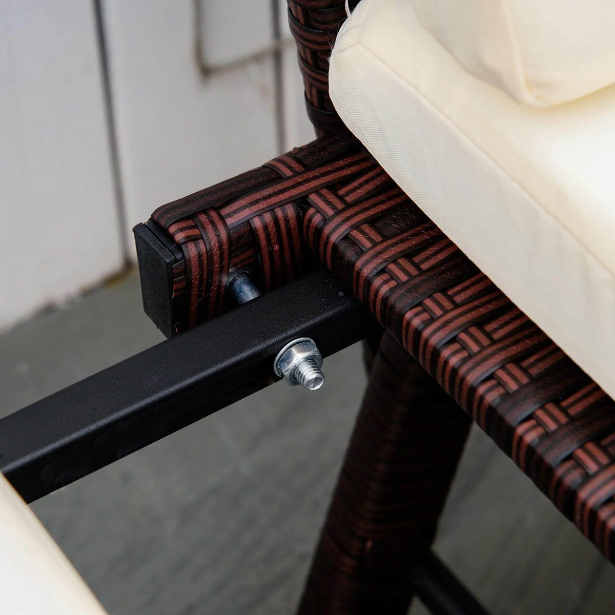 Rattan daybed armrest detail with patterned wicker weave and black metal support