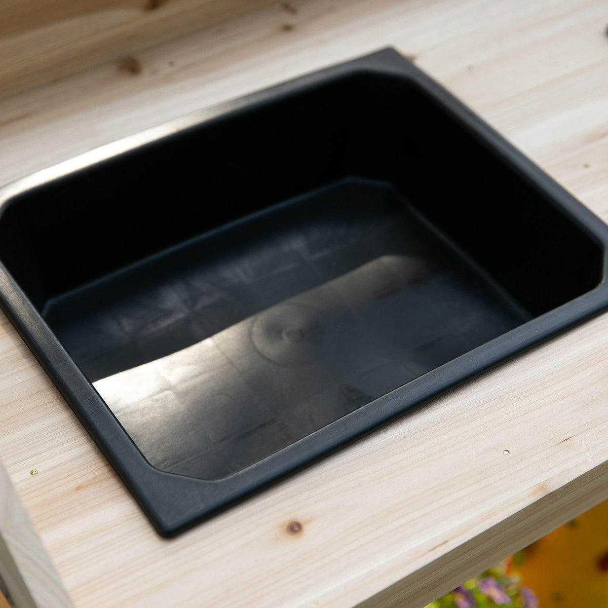Black plastic sink insert in a wooden potting bench tabletop