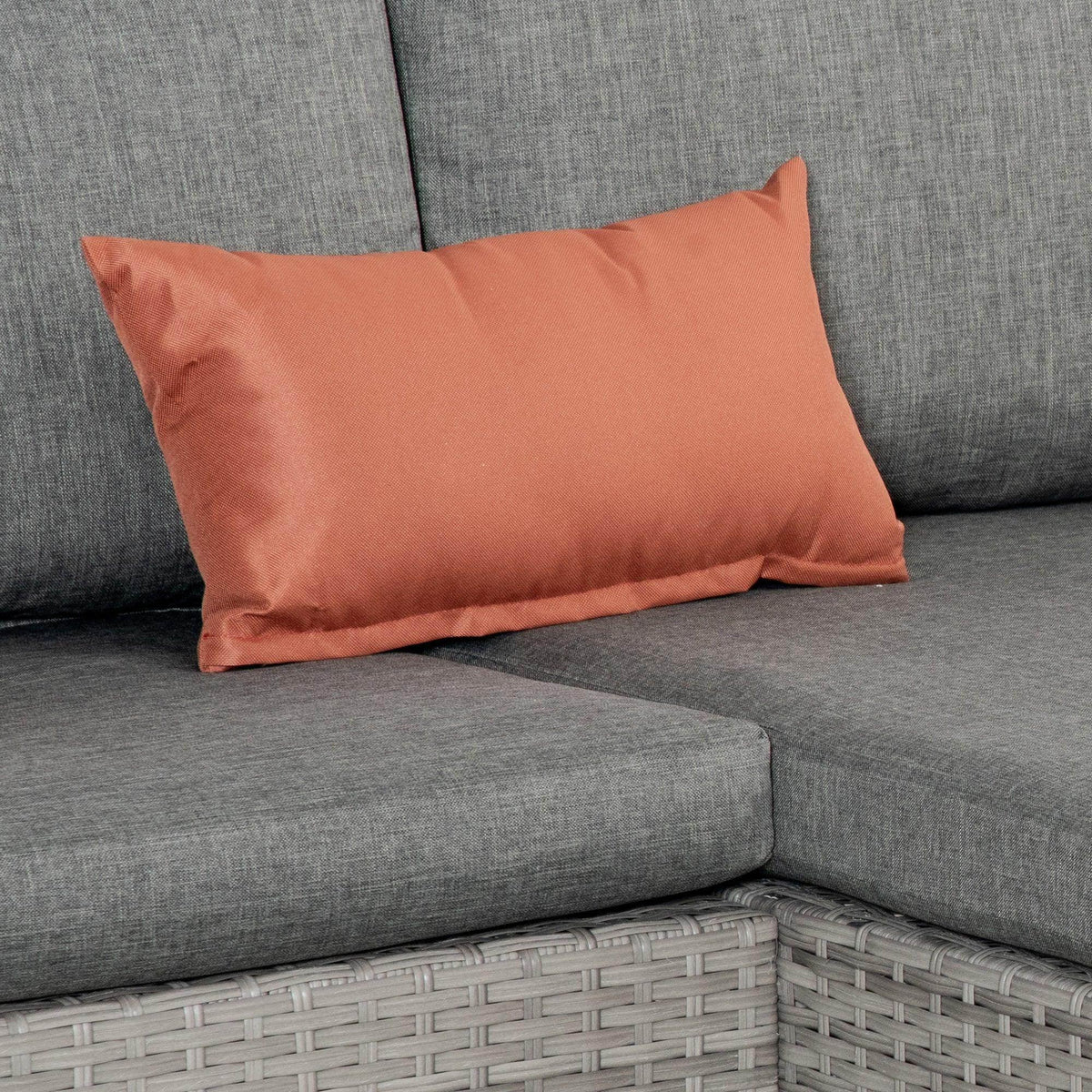 Gray corner sofa seat cushion with burnt orange rectangular throw pillow
