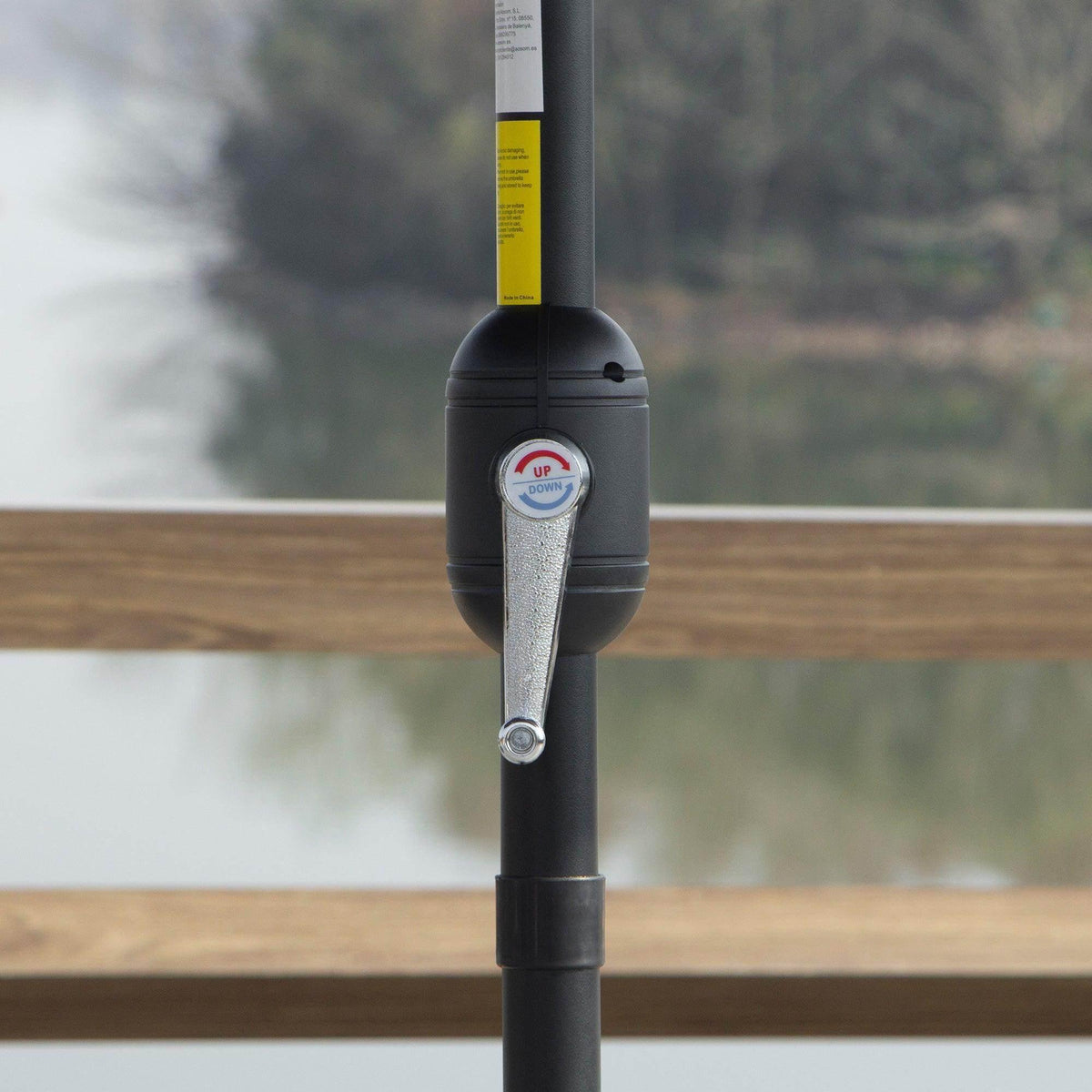 Manual crank control on blue umbrella pole with locking knob close-up