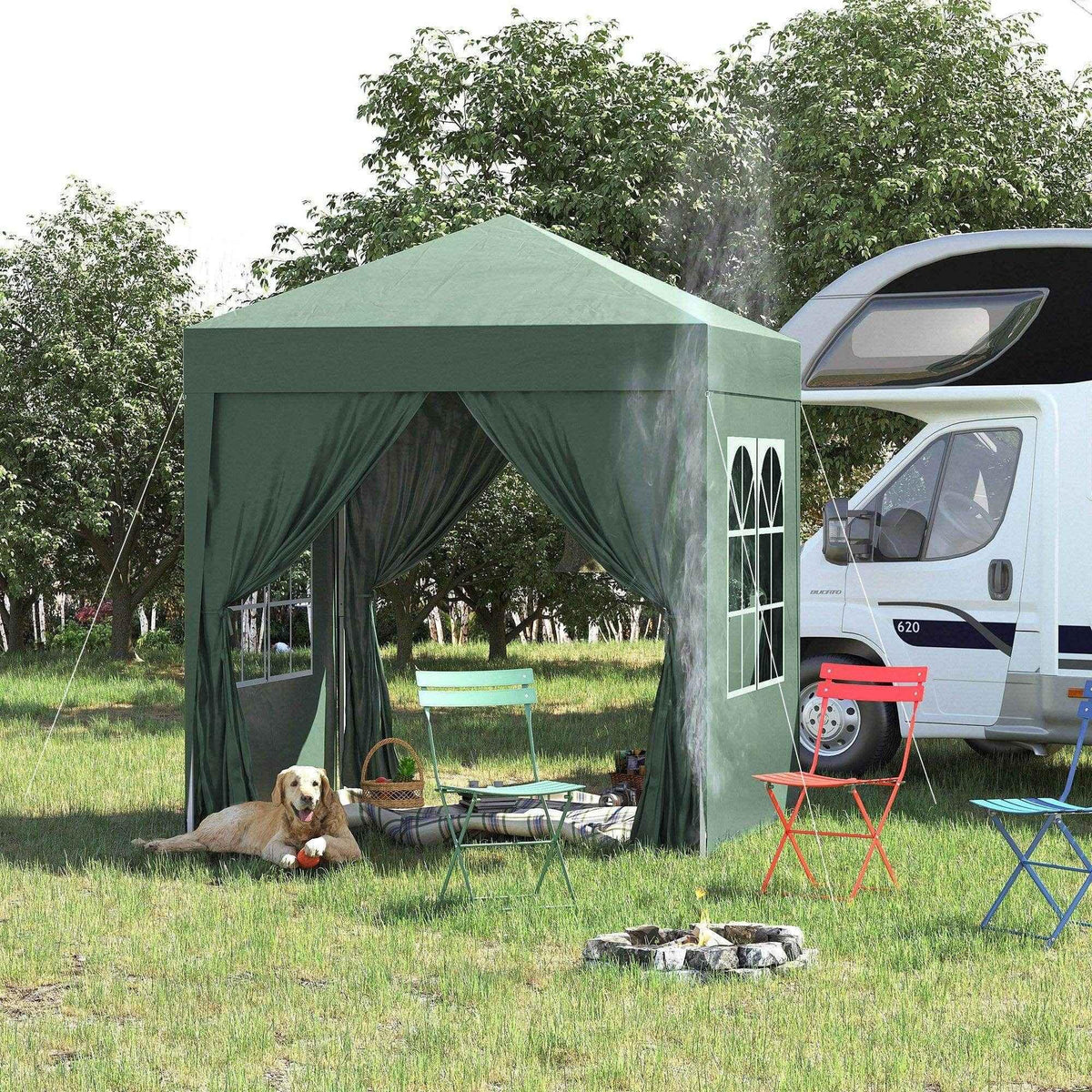 Green pop-up gazebo with side curtains, outdoor chairs, dog, and campfire beside RV in grassy yard