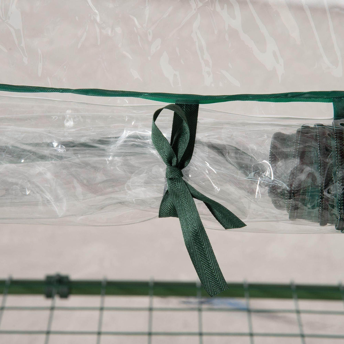 Green roll-up door tie ribbon on clear PVC greenhouse cover