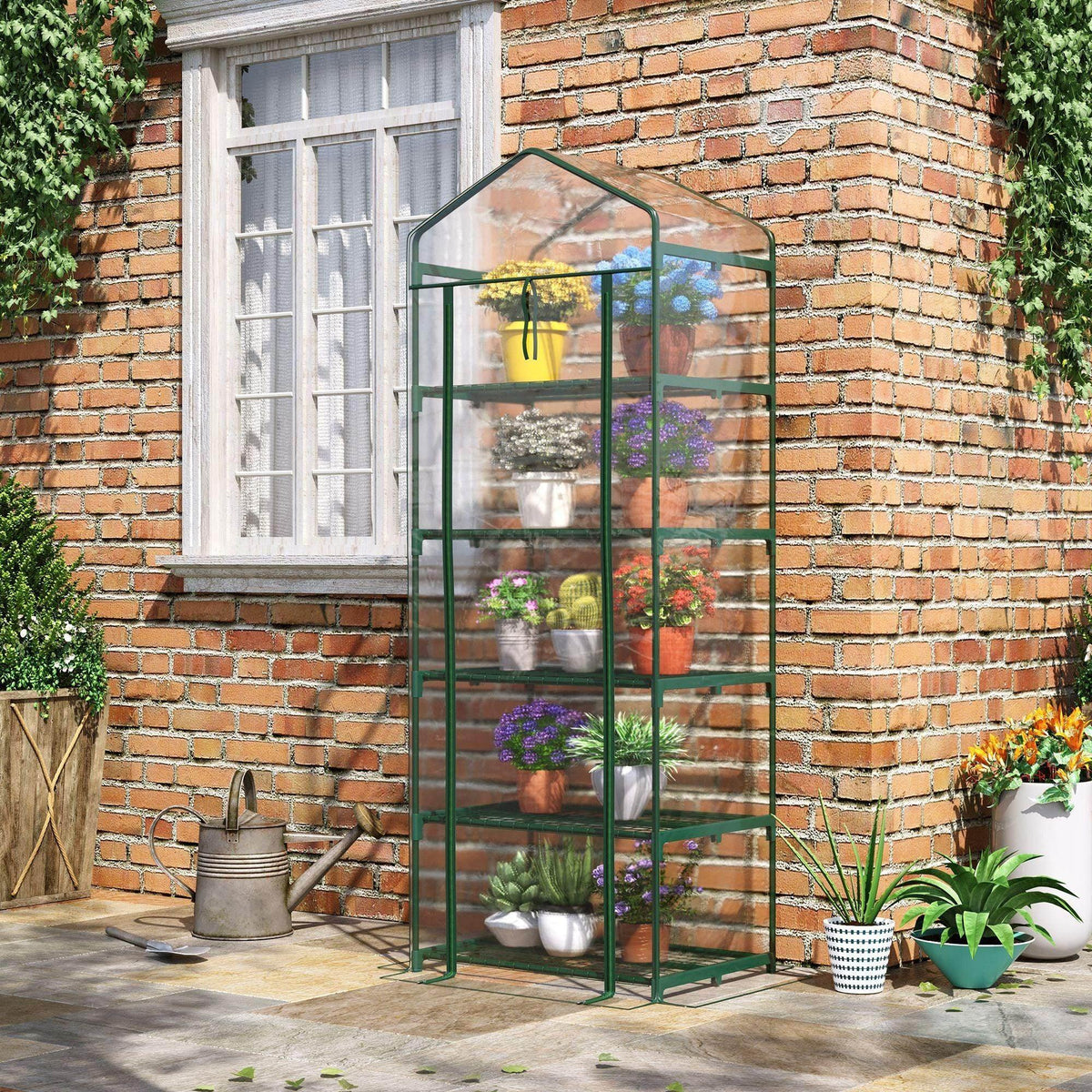 Portable greenhouse with green metal frame and clear cover, standing outdoors with shelves