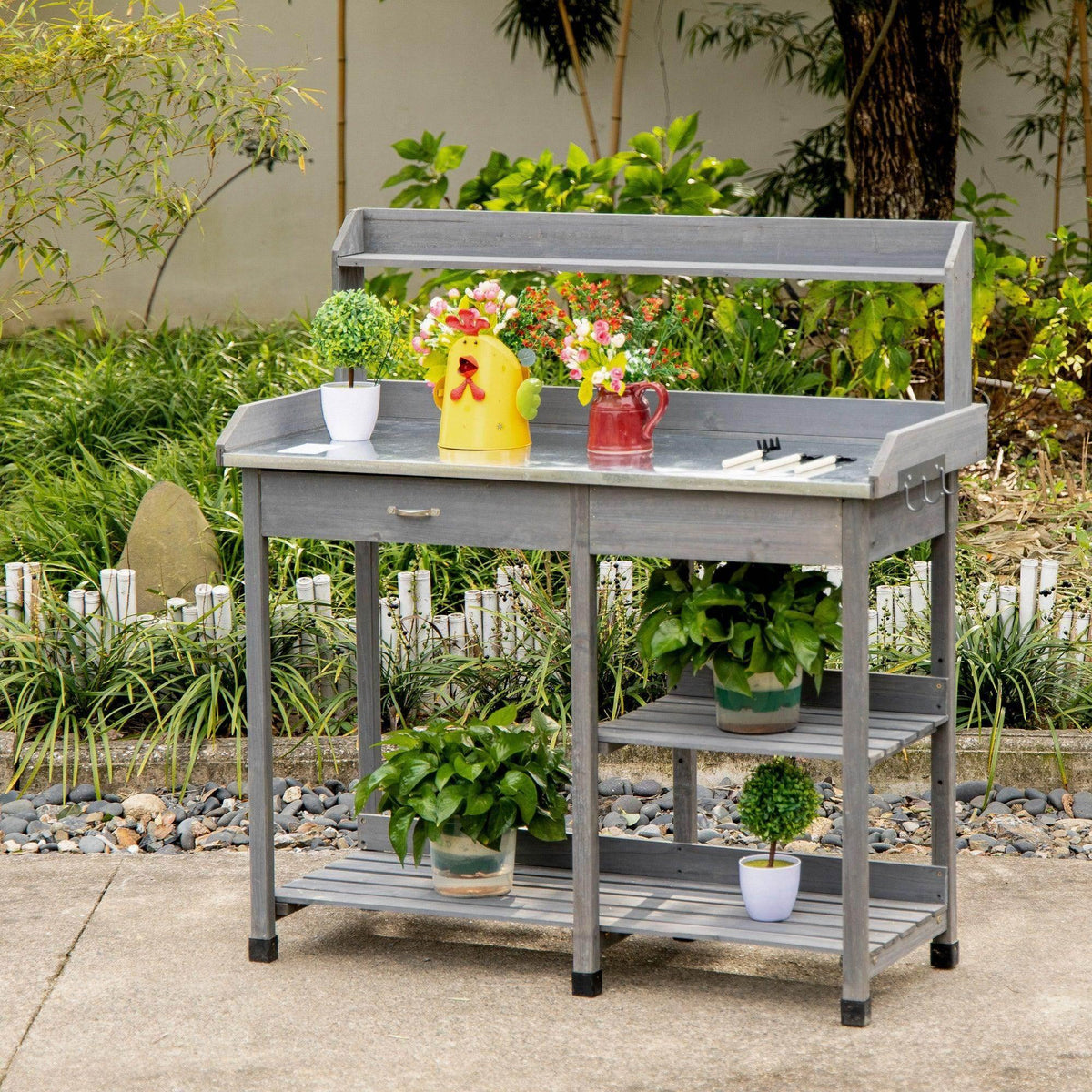 Gray wooden potting table with galvanized metal top, lower shelf, and side tool hooks