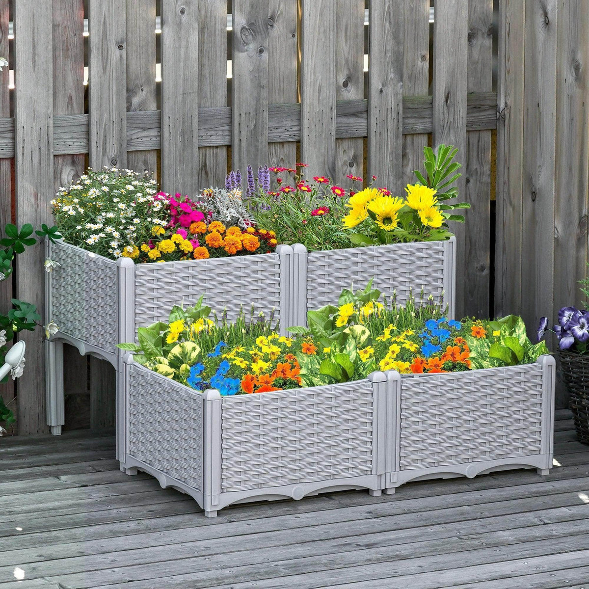 Light grey raised garden bed set with woven sides, filled with colorful flowers.