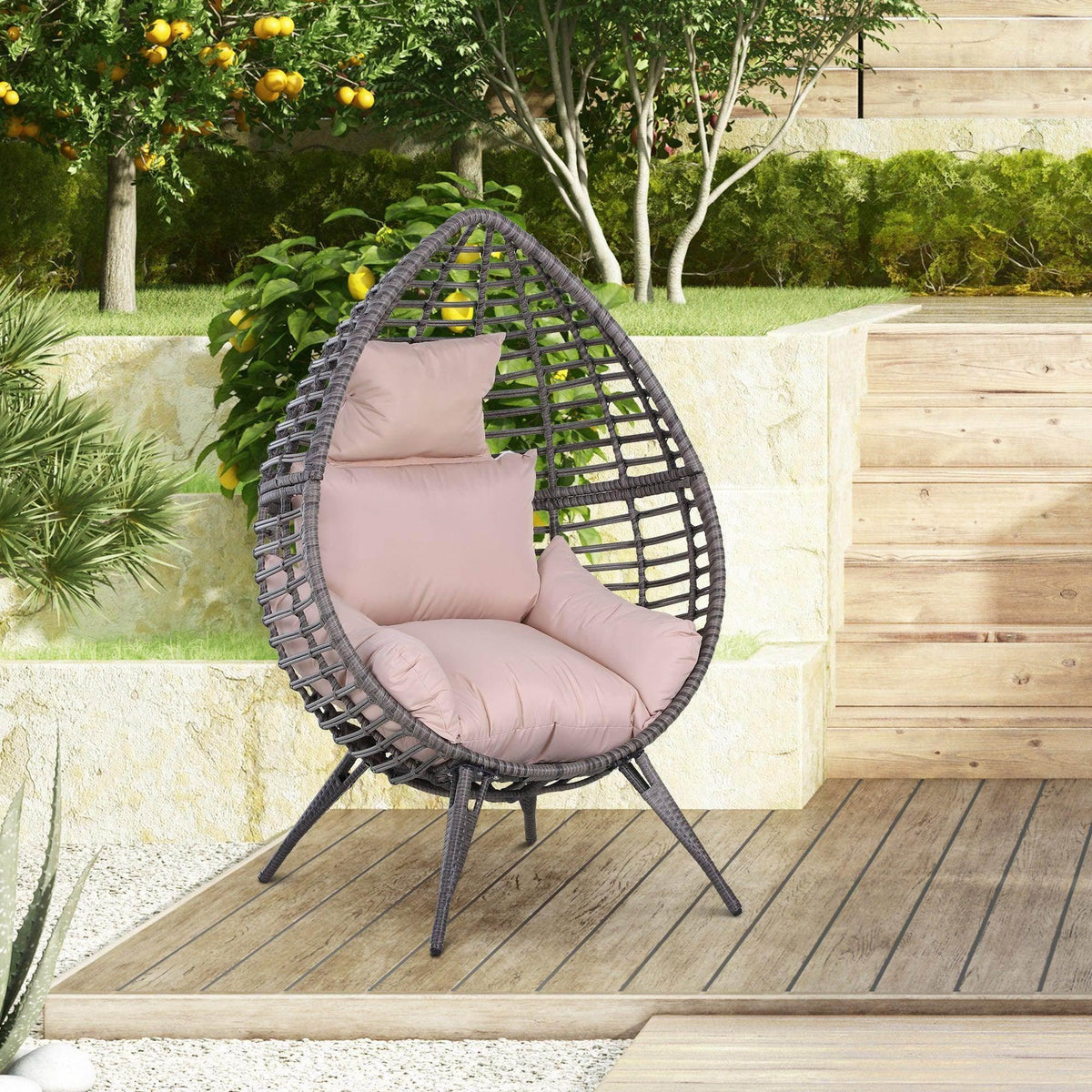 Teardrop rattan egg chair with light pink cushions and dark woven frame on legs