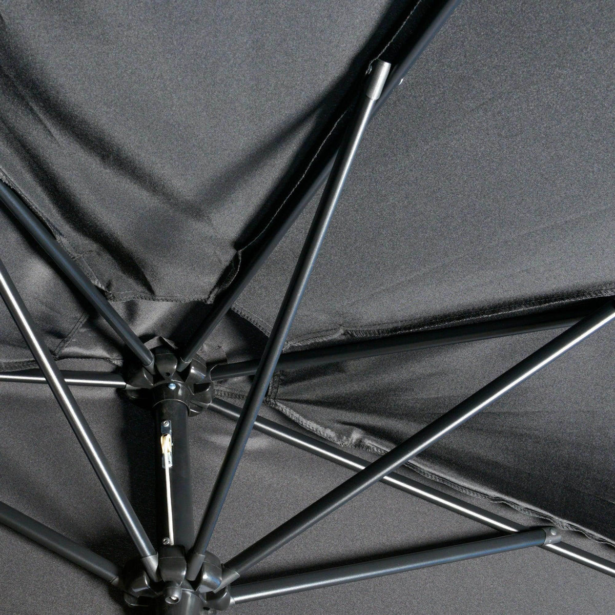 Black patio umbrella close-up of metal ribs and central hub on the canopy frame.