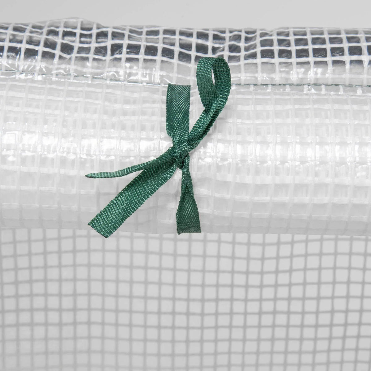 Close-up of clear PE mesh greenhouse cover tied with green fabric ribbon