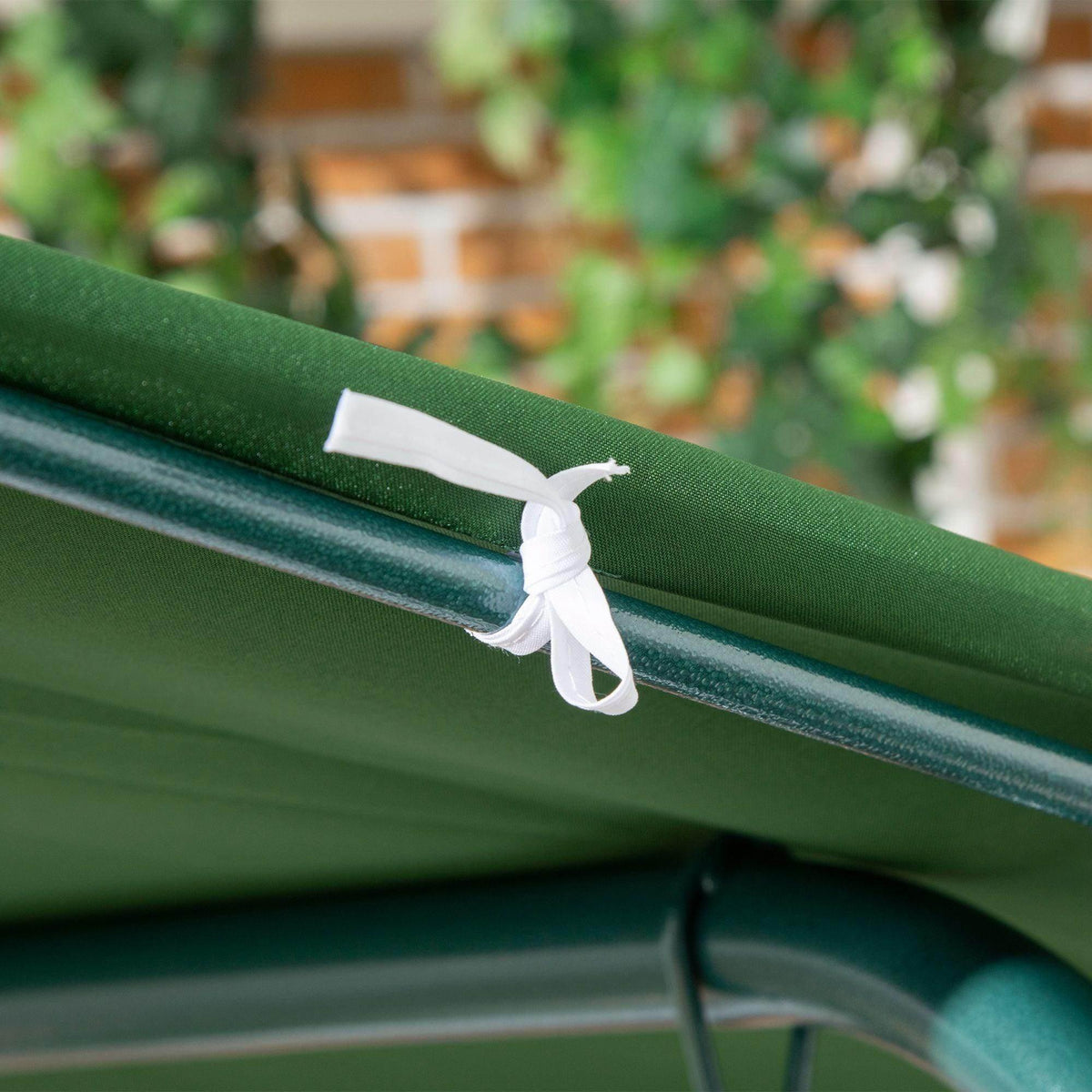 Green canopy fabric with white tie strap on steel swing frame