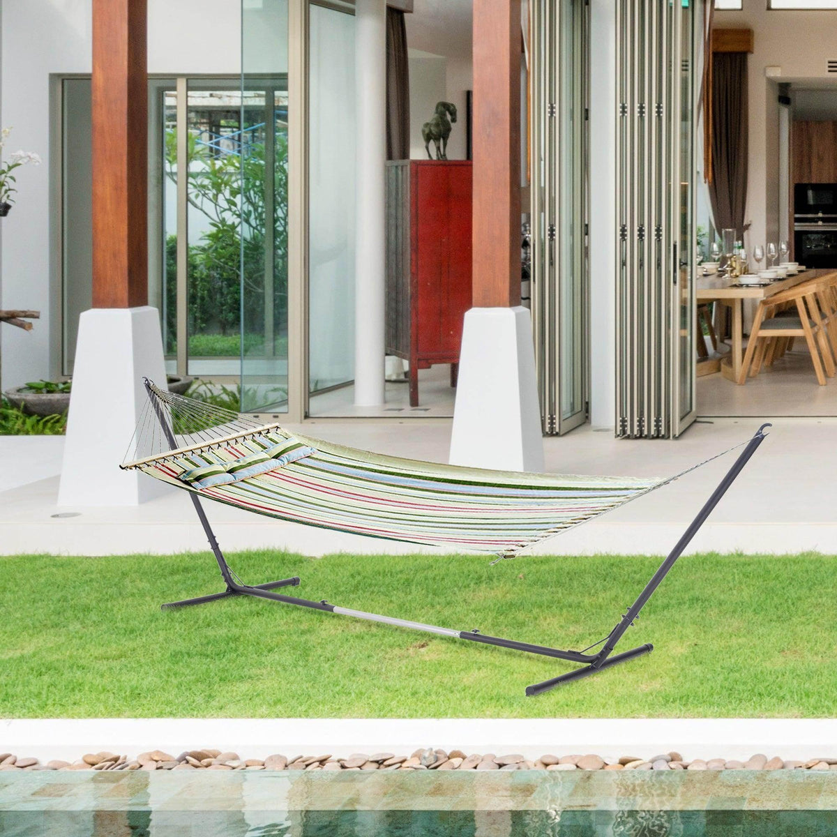 Freestanding metal hammock stand with black frame and striped hammock on grass