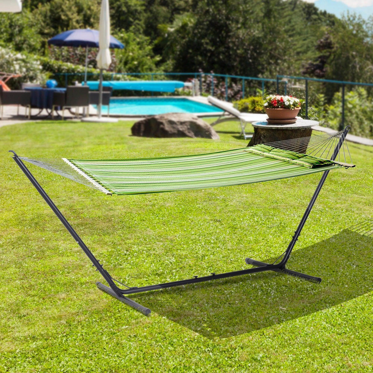 Striped green hammock on a black metal stand outdoors on grass