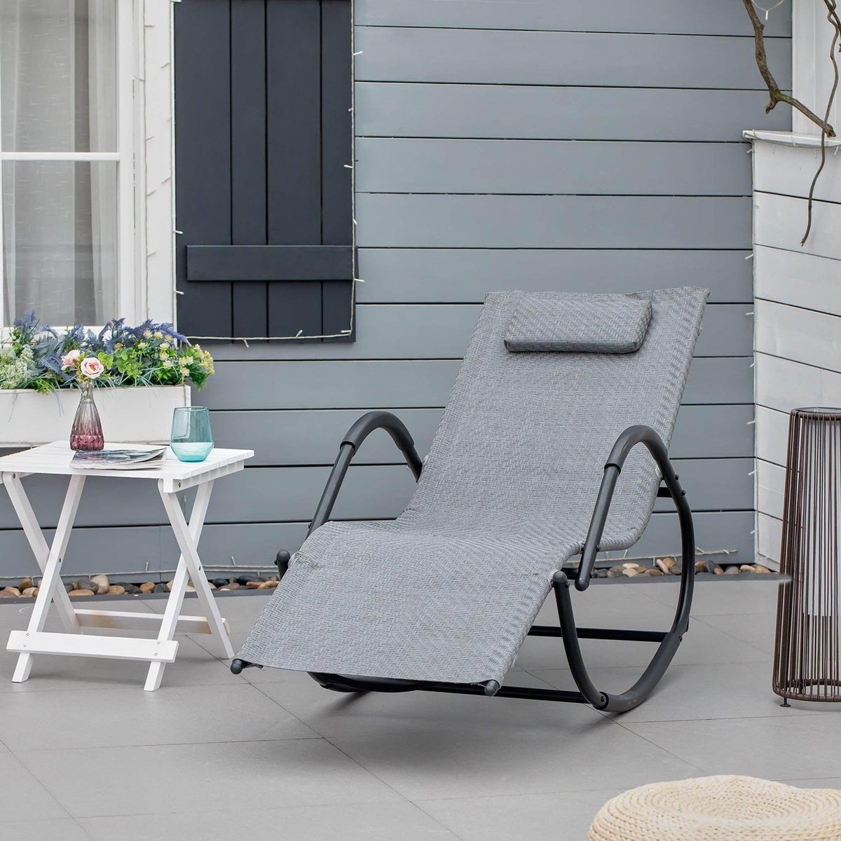 Grey fabric zero-gravity rocking chair with curved black metal base and padded headrest