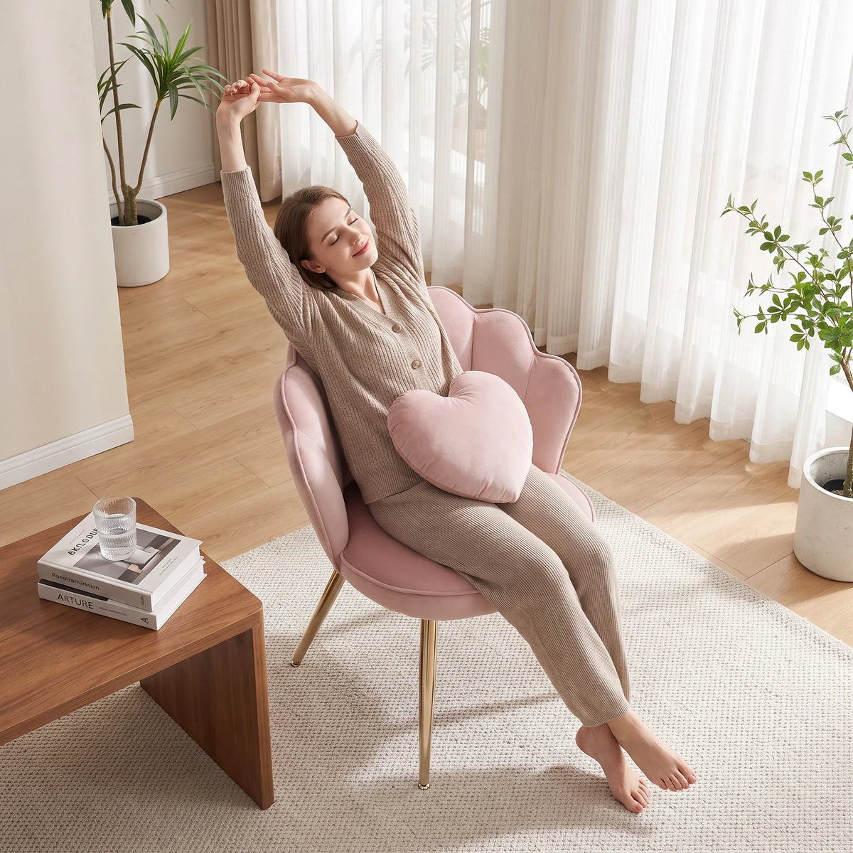 Soft pink velvet accent chair with heart pillow and gold-tone legs in relaxed pose