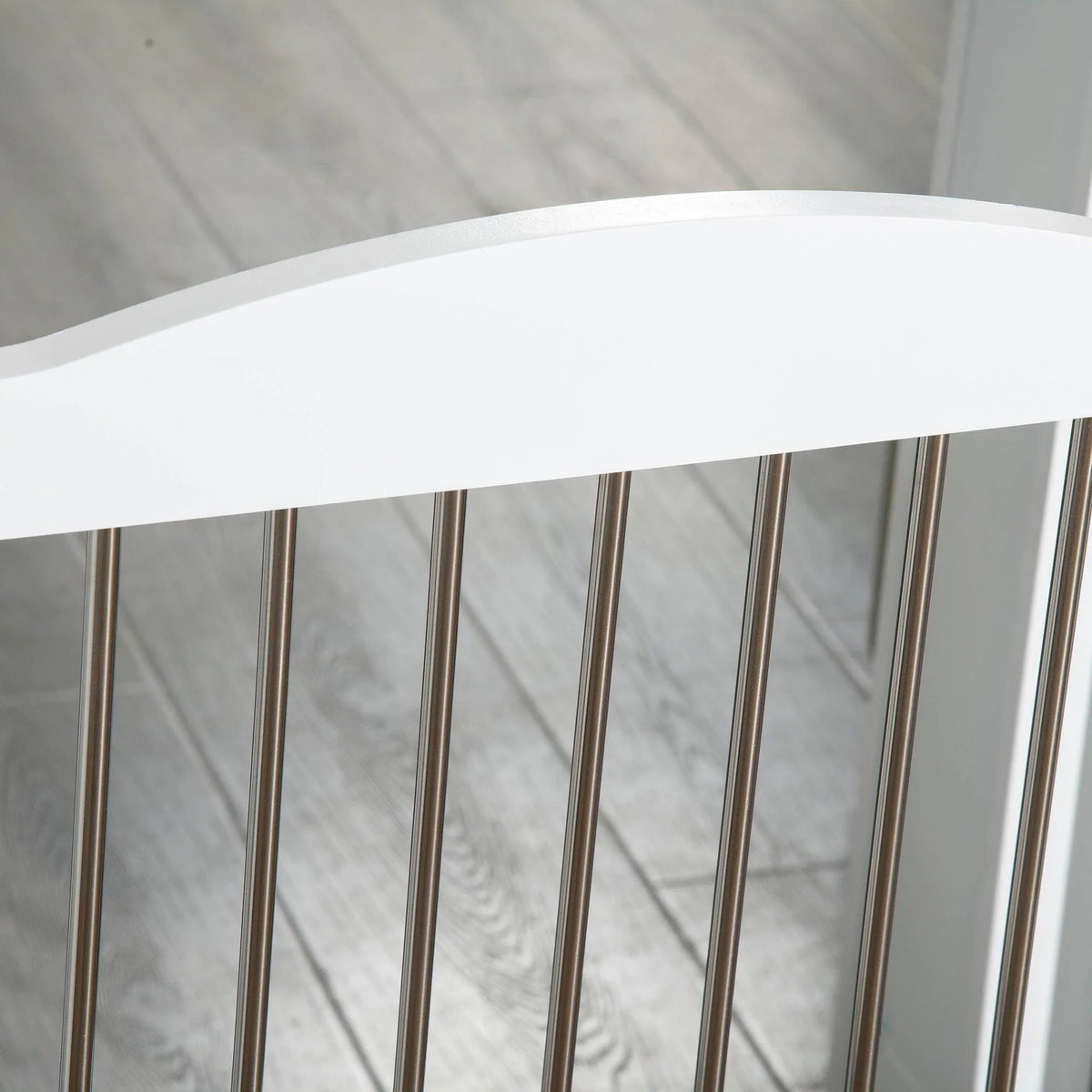 Close-up of white dog gate vertical metal bars and top rail.
