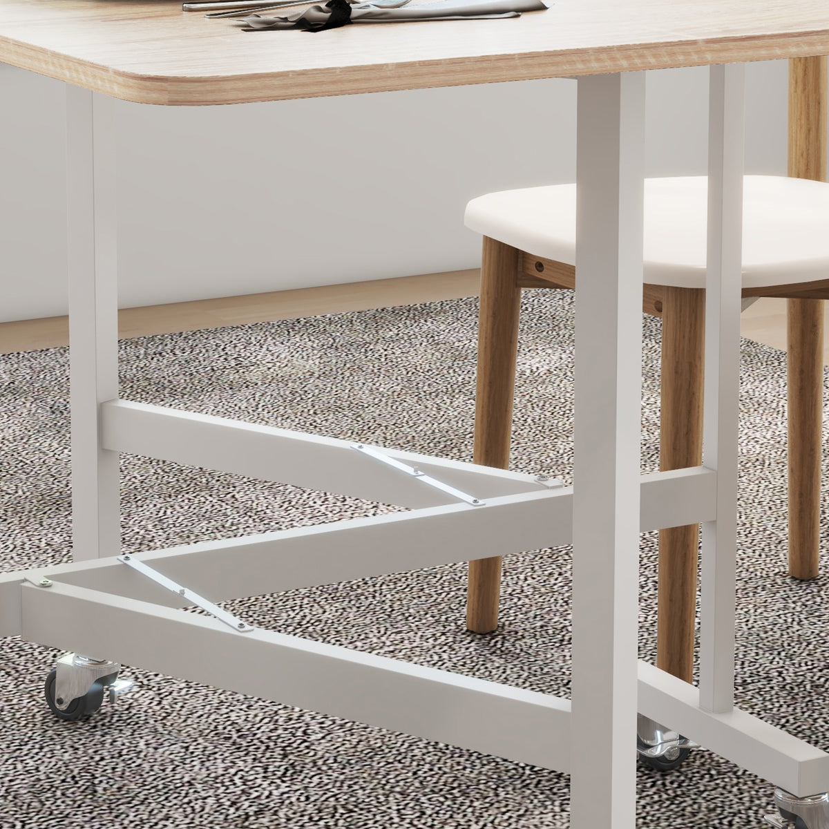 Underside view of drop-leaf dining table with white supports and caster wheels