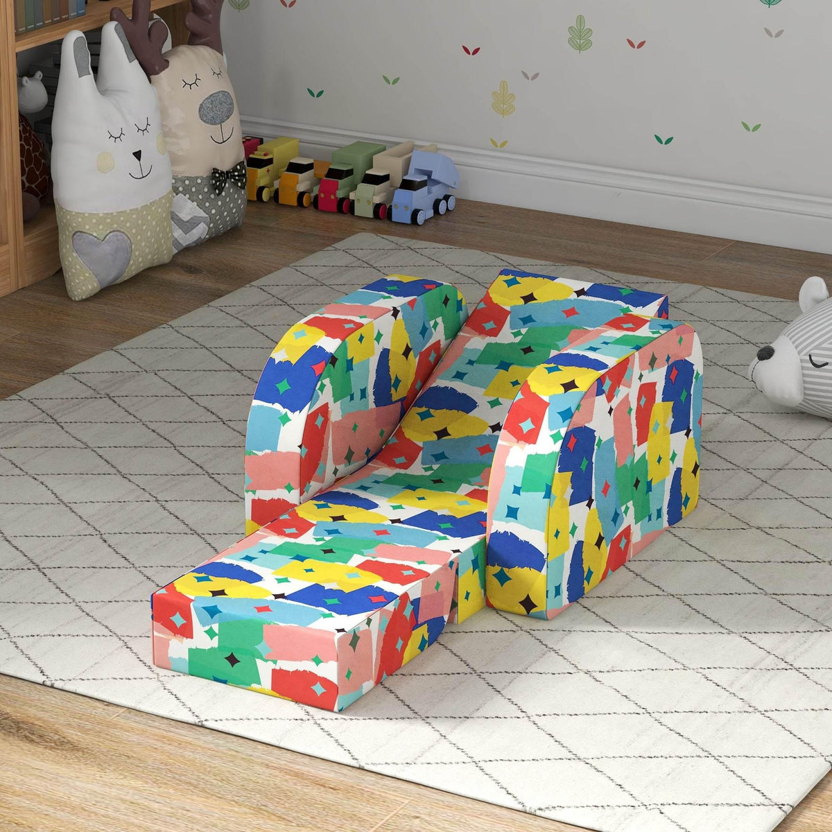 Colorful foldable toddler armchair, padded seat and back, angled view on floor mat.