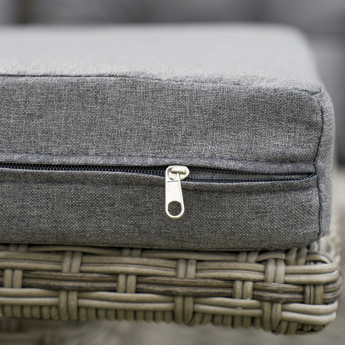 Outdoor cushion cover zipper detail on gray sofa seat with woven rattan base