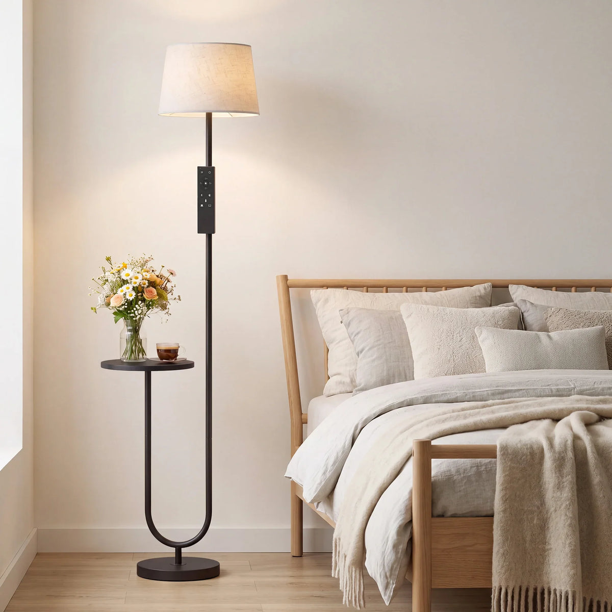 Tall floor lamp with linen shade and round side shelf beside bed
