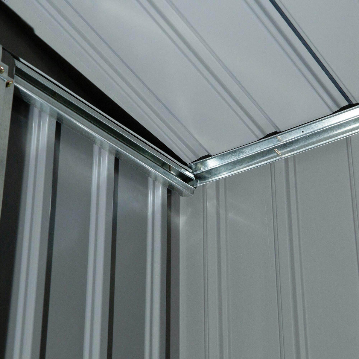 Galvanized metal garden shed roof corner with steel frame and panel seams.