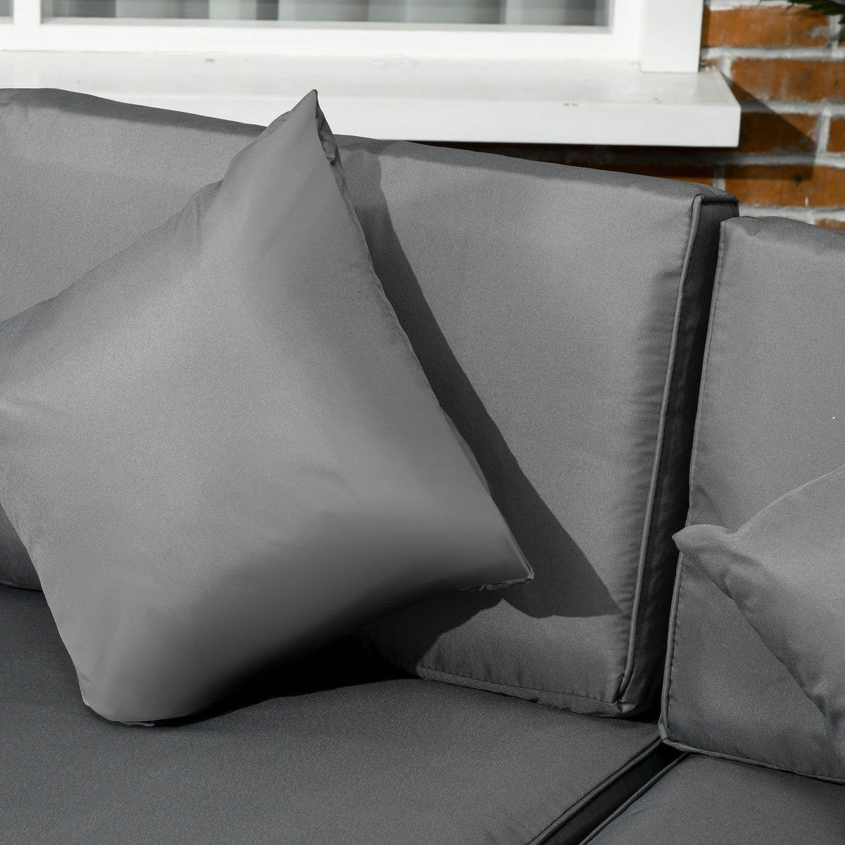 Grey cushion set with throw pillows on rattan sectional sofa armrest