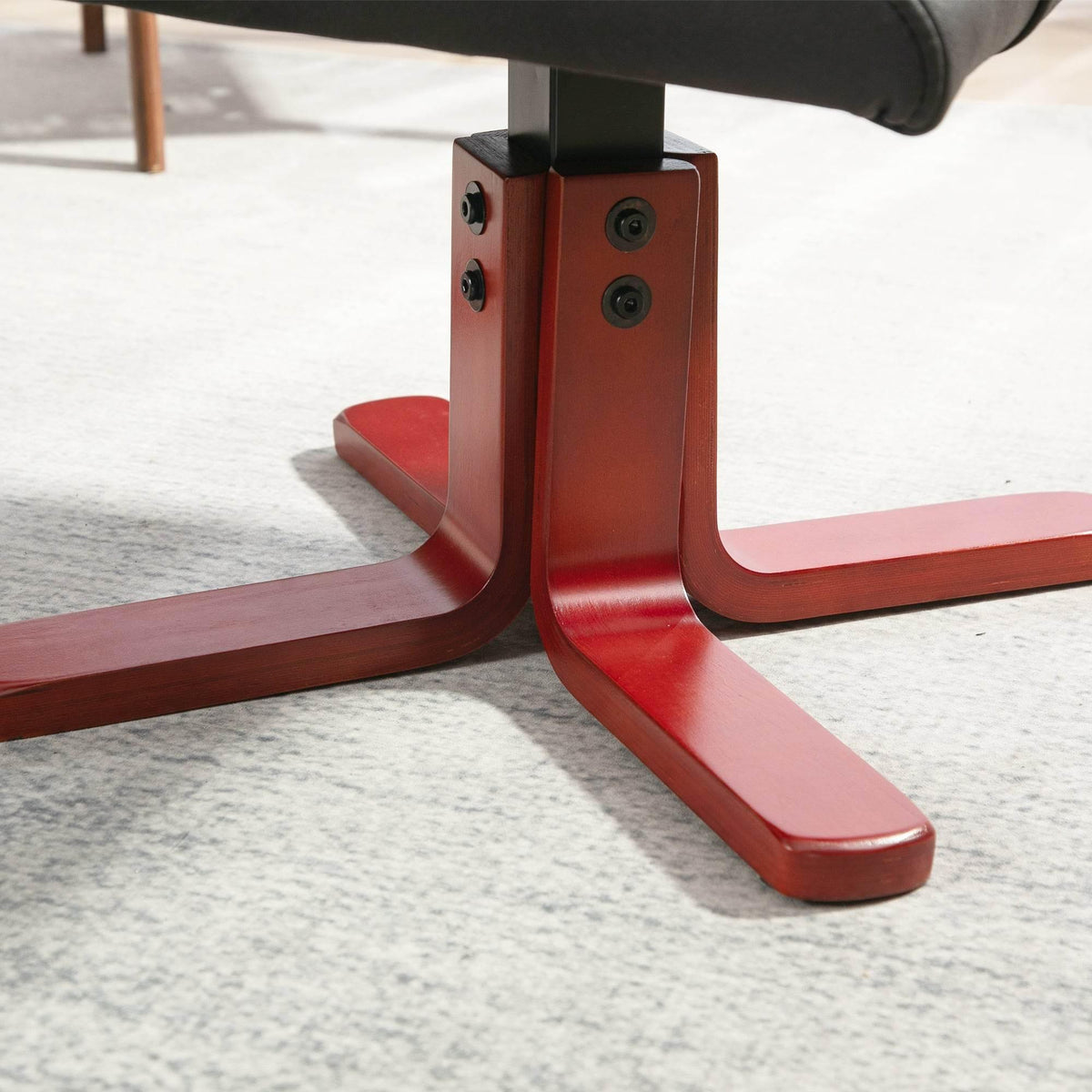 Close-up of recliner base: red metal legs with black faux leather seat support.